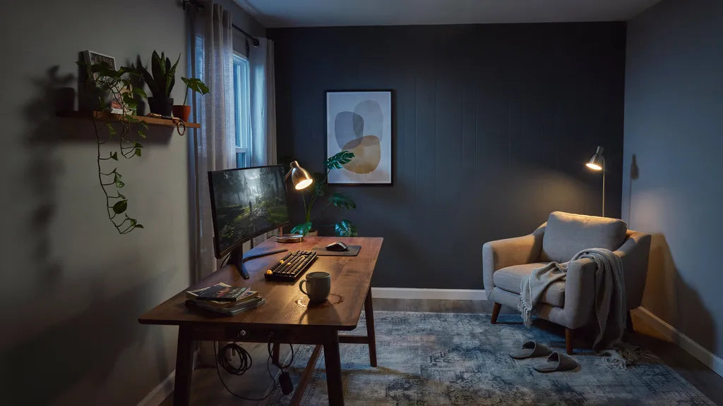 Gaming room with a dark accent wall, one large framed art print above the desk and warm layered lamp light