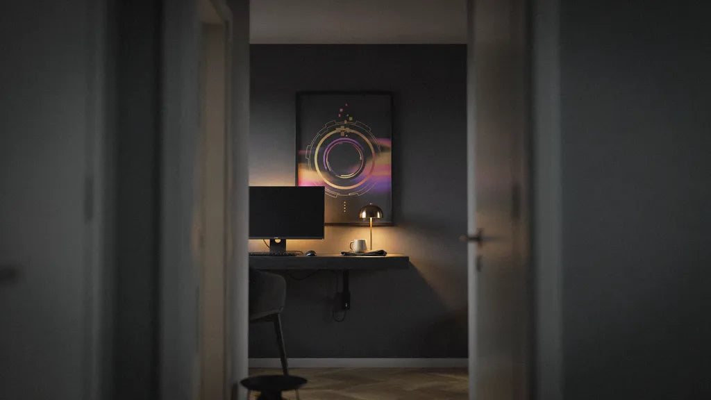 Small gaming room with a wall-mounted desk, warm bias lighting behind the monitor and one large framed art print above the desk