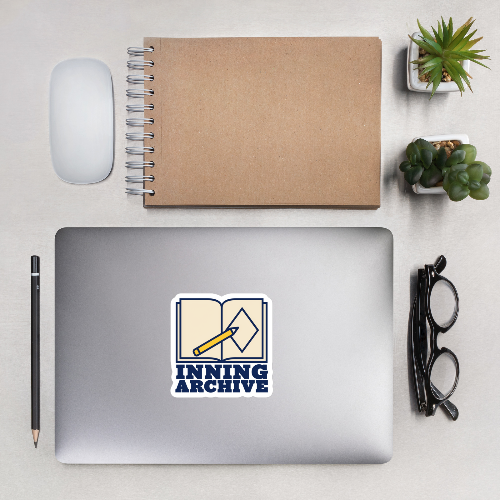 INNING ARCHIVE 4 inch baseball sticker on a laptop in an overhead indoor desk with laptop, notebook, mouse, glasses and plants. Styling props are not included.