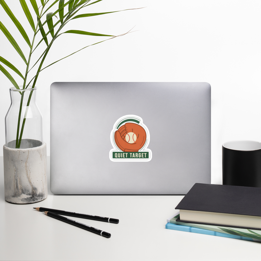 QUIET TARGET 4 inch baseball sticker on a laptop in a front-facing indoor desk scene with books, a mug and a plant. Styling props are not included.