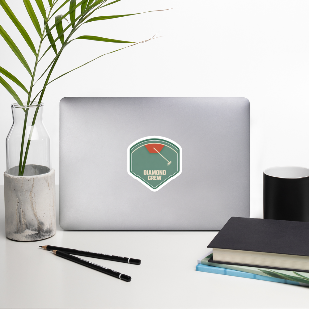 DIAMOND CREW 4 inch baseball sticker on a laptop in a front-facing indoor desk scene with books, a mug and a plant. Styling props are not included.