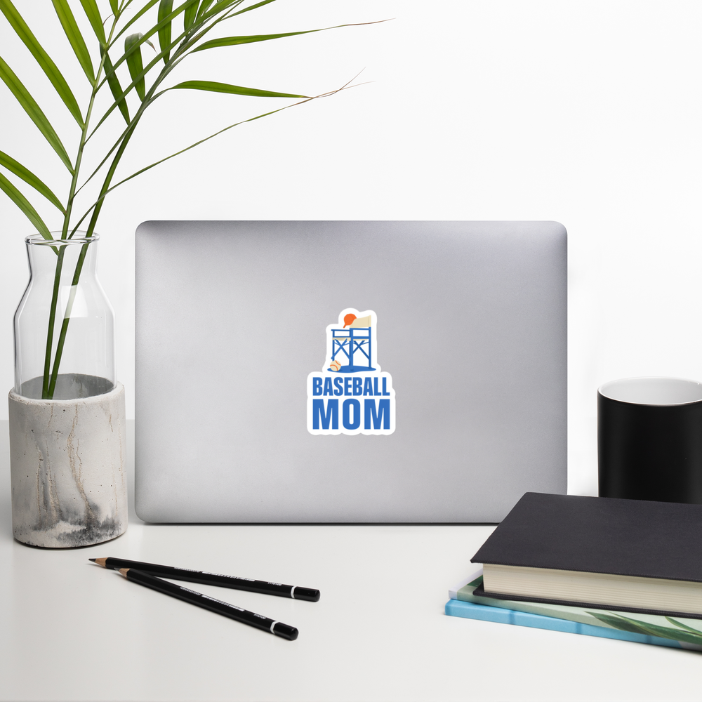 BASEBALL MOM 4 inch baseball sticker on a laptop in a front-facing indoor desk scene with books, a mug and a plant. Styling props are not included.