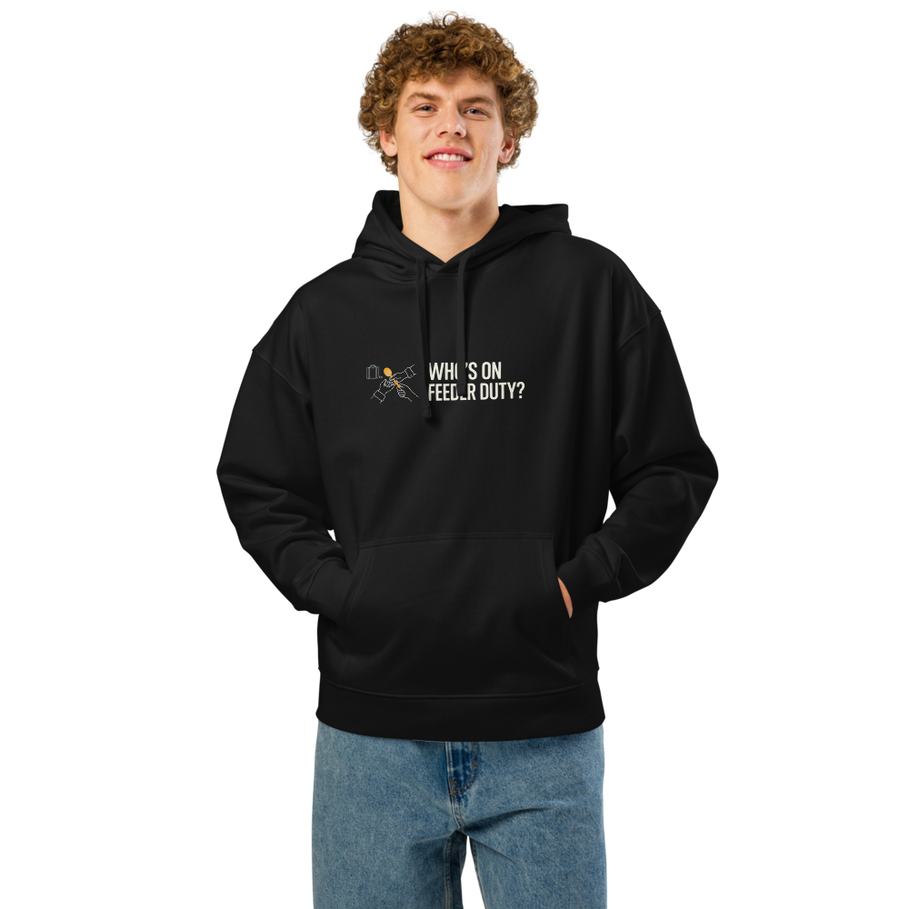 Man wearing the black bird lover hoodie with two hands passing a seed scoop beside WHO'S ON FEEDER DUTY?