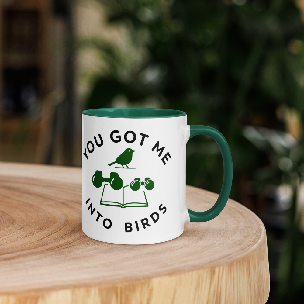 Bird watcher gift mug with dark green inside on a wooden table with plants behind