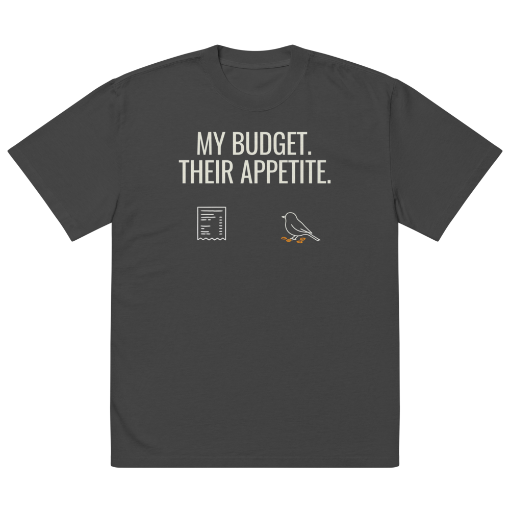 The faded black bird watcher shirt laid flat, showing MY BUDGET. THEIR APPETITE. above a receipt and a pecking songbird