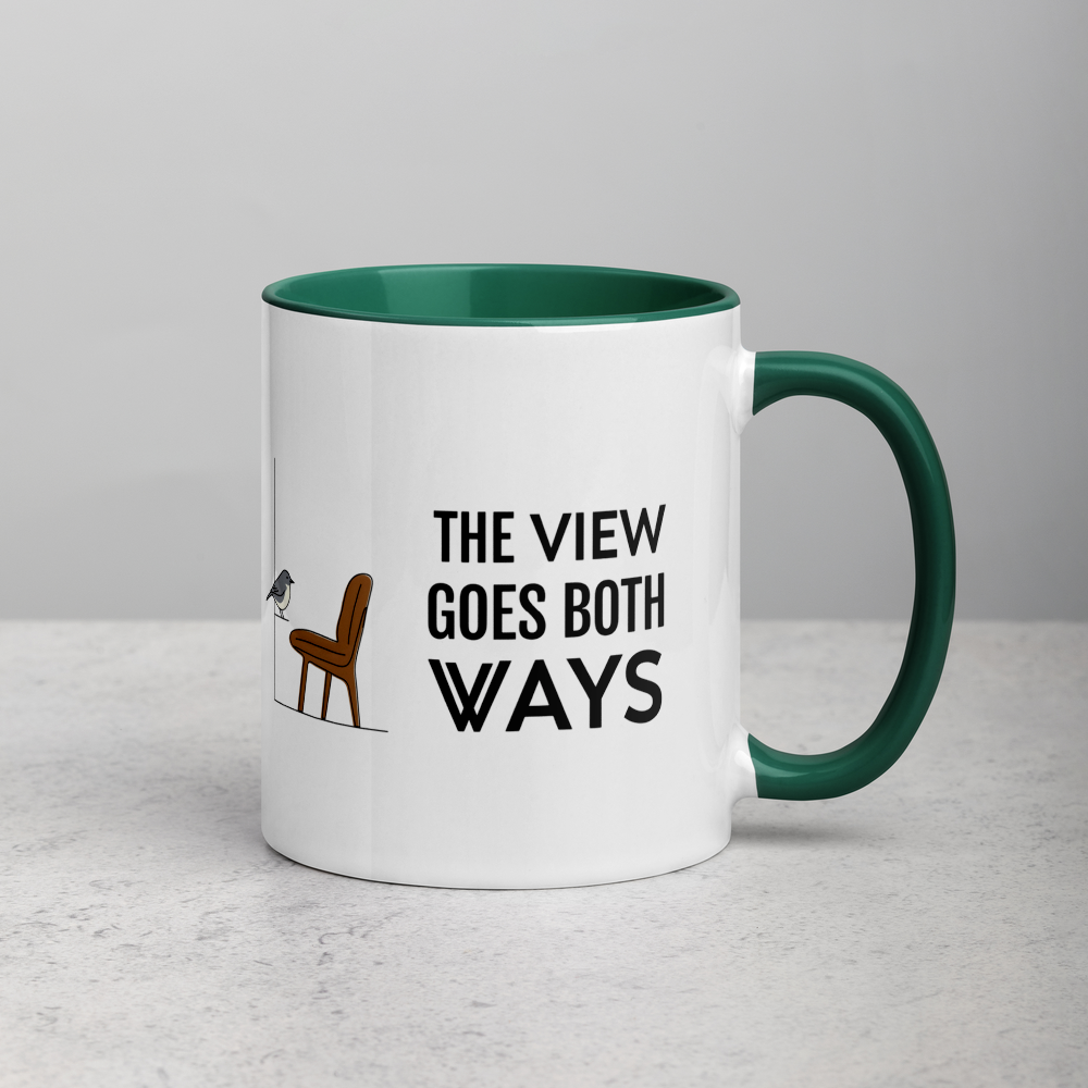 Bird watching mug with dark green inside on a stone counter, showing THE VIEW GOES BOTH WAYS beside a bird on the sill and an empty chair