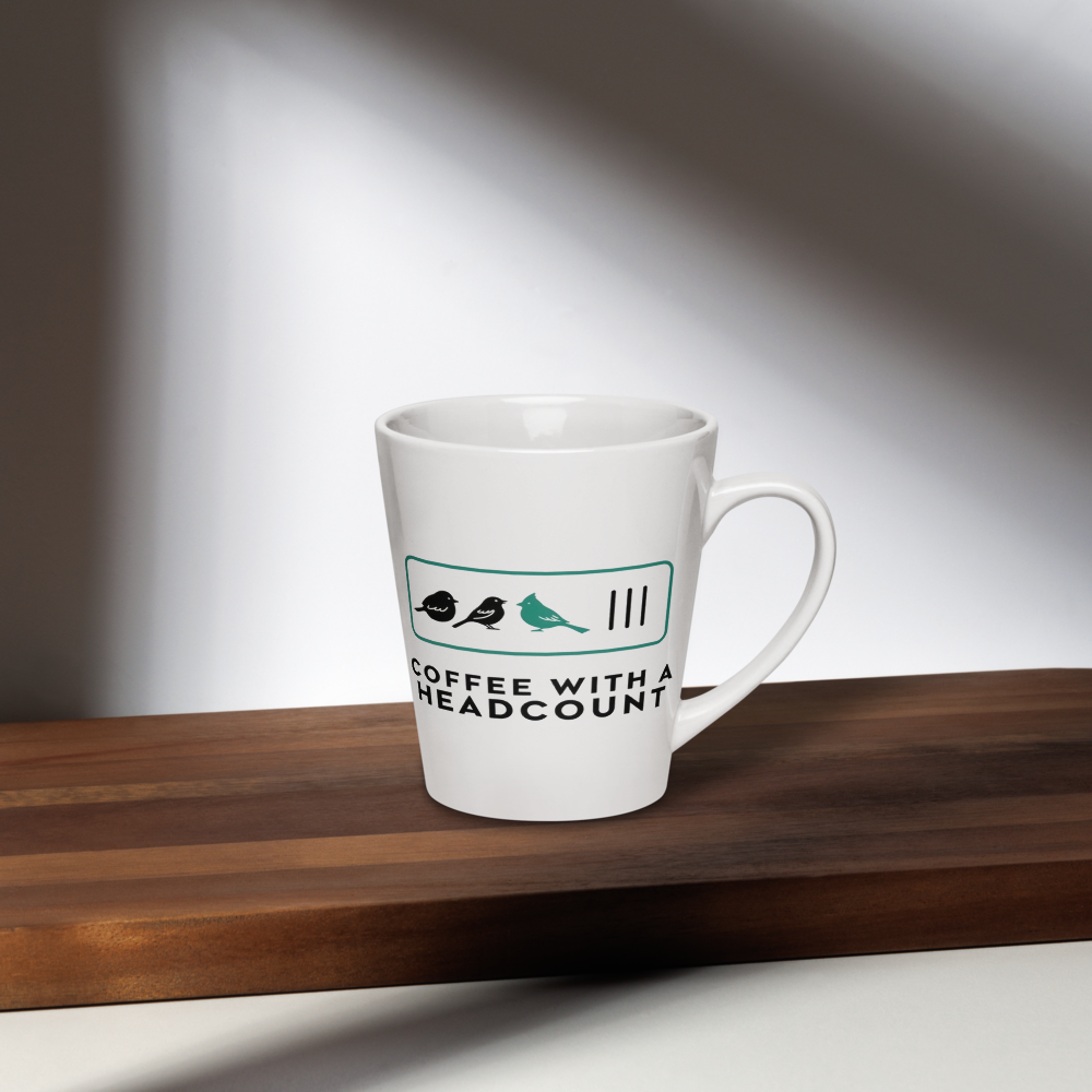 Birder gift mug on a dark wood shelf in window light, showing three birds and three tally marks over COFFEE WITH A HEADCOUNT