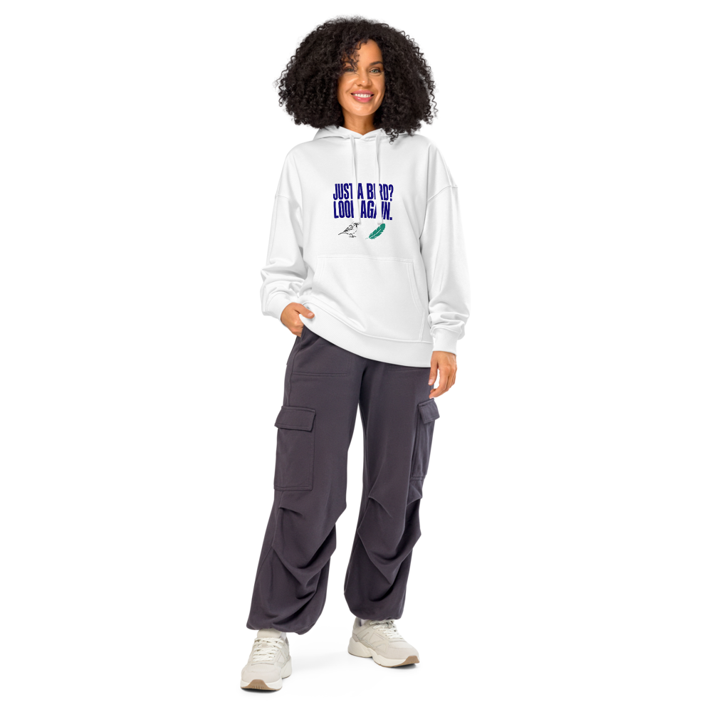 Woman wearing the white birder hoodie with JUST A BIRD? LOOK AGAIN. above a sparrow and a feather