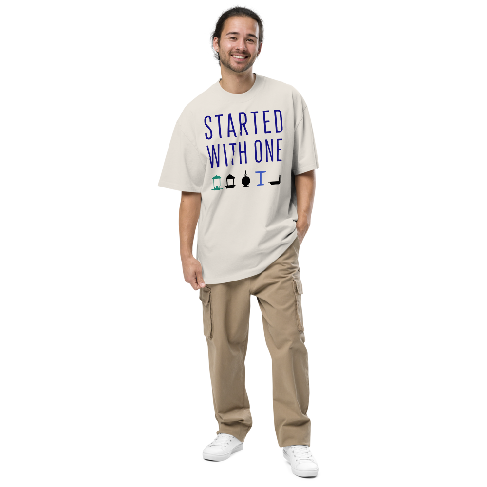 Man wearing the faded bone birding shirt with STARTED WITH ONE above a row of five bird feeders