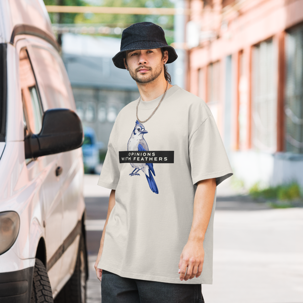 Man in the faded bone blue jay shirt on a city street, showing a blue jay under an OPINIONS WITH FEATHERS banner