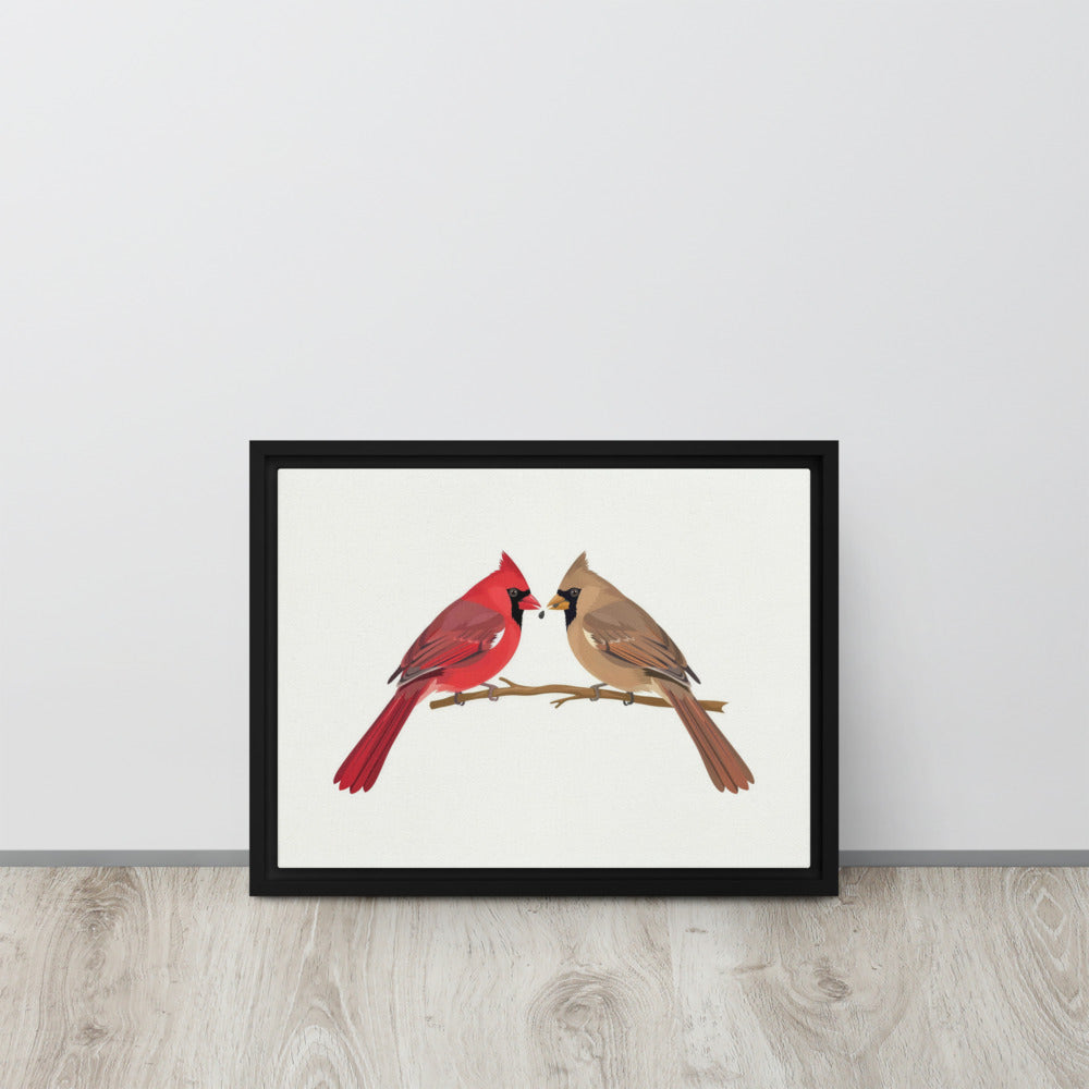 A Seed Shared framed cardinal canvas leaning against a wall on a wood floor