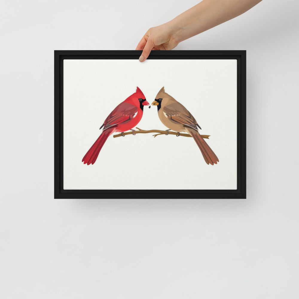 Hand hanging the A Seed Shared framed cardinal canvas on a white wall
