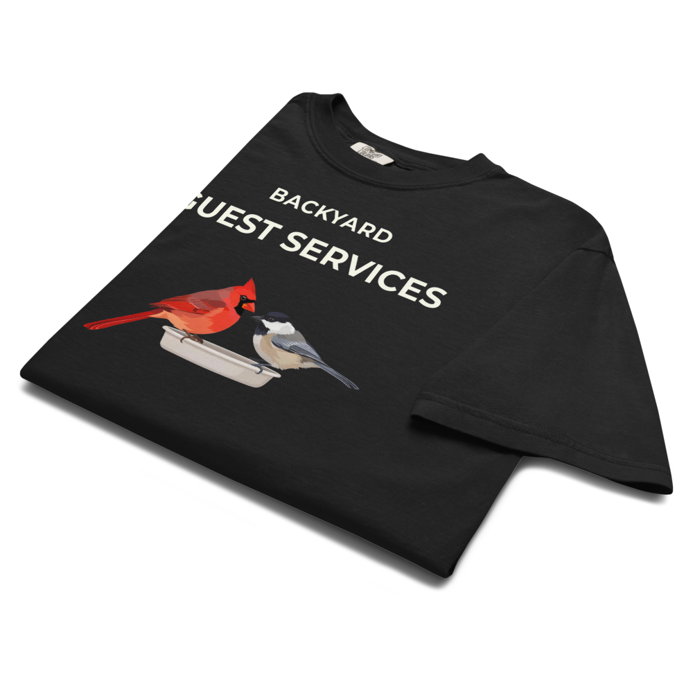 The black cardinal shirt folded, showing BACKYARD GUEST SERVICES above a cardinal and a chickadee at a tray feeder