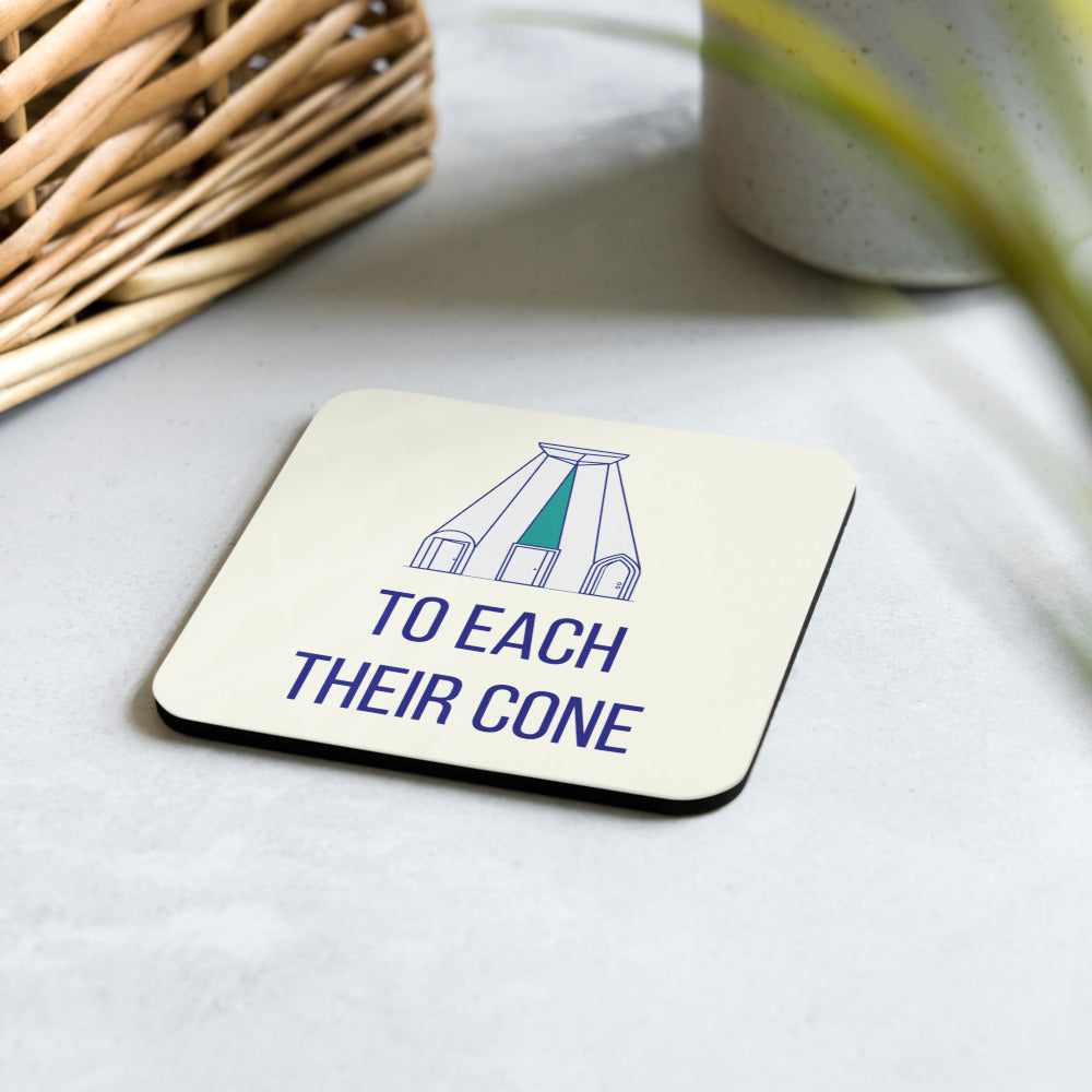 To Each Their Cone dark-sky coaster on a pale stone table beside a wicker basket and a potted plant