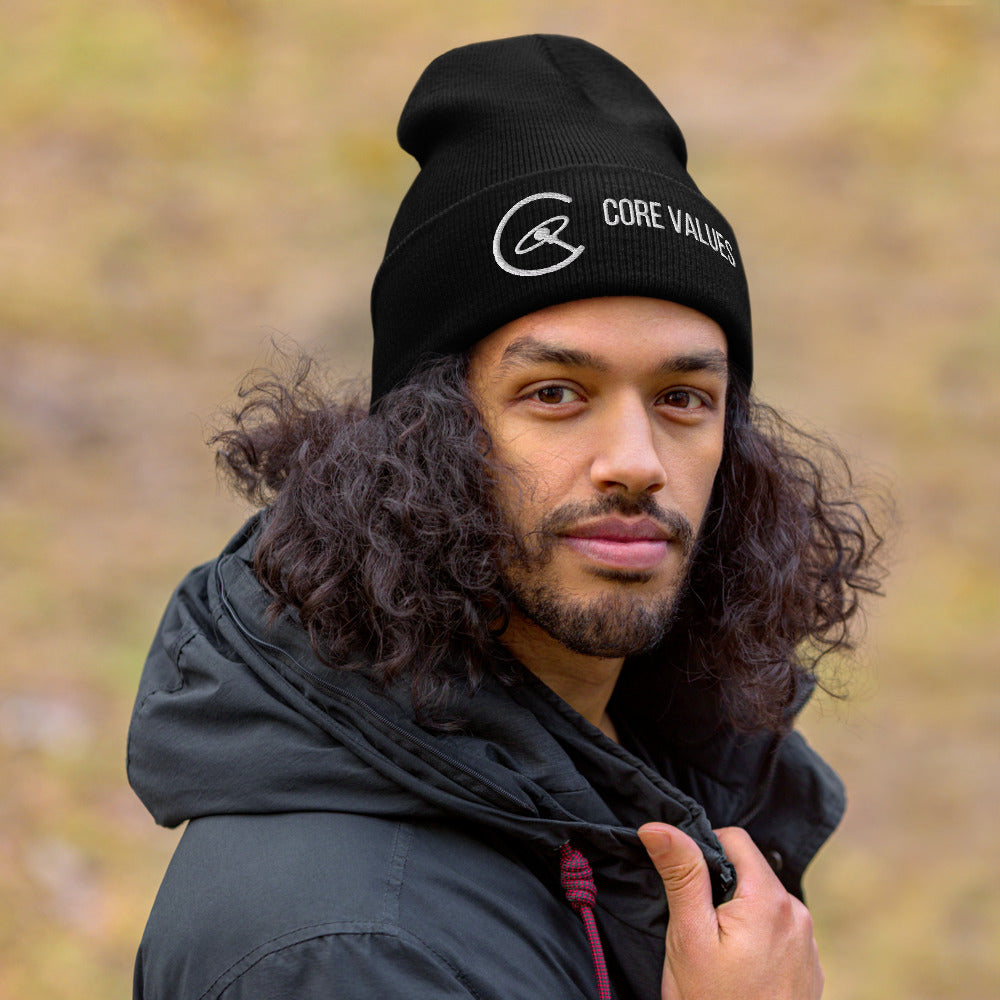 Man with long curly hair wearing the black Core Values galaxy beanie outdoors on an autumn day