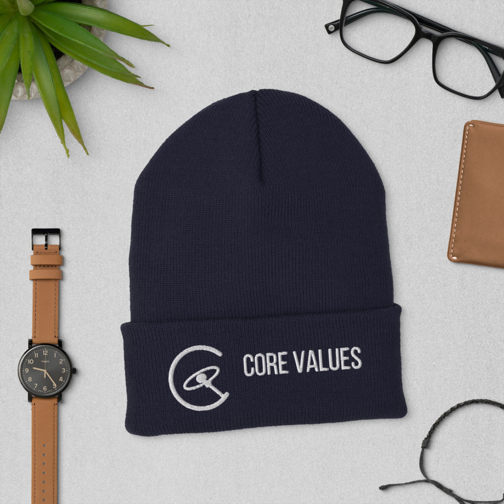 Navy Core Values galaxy beanie laid flat beside a watch, glasses and a leather wallet