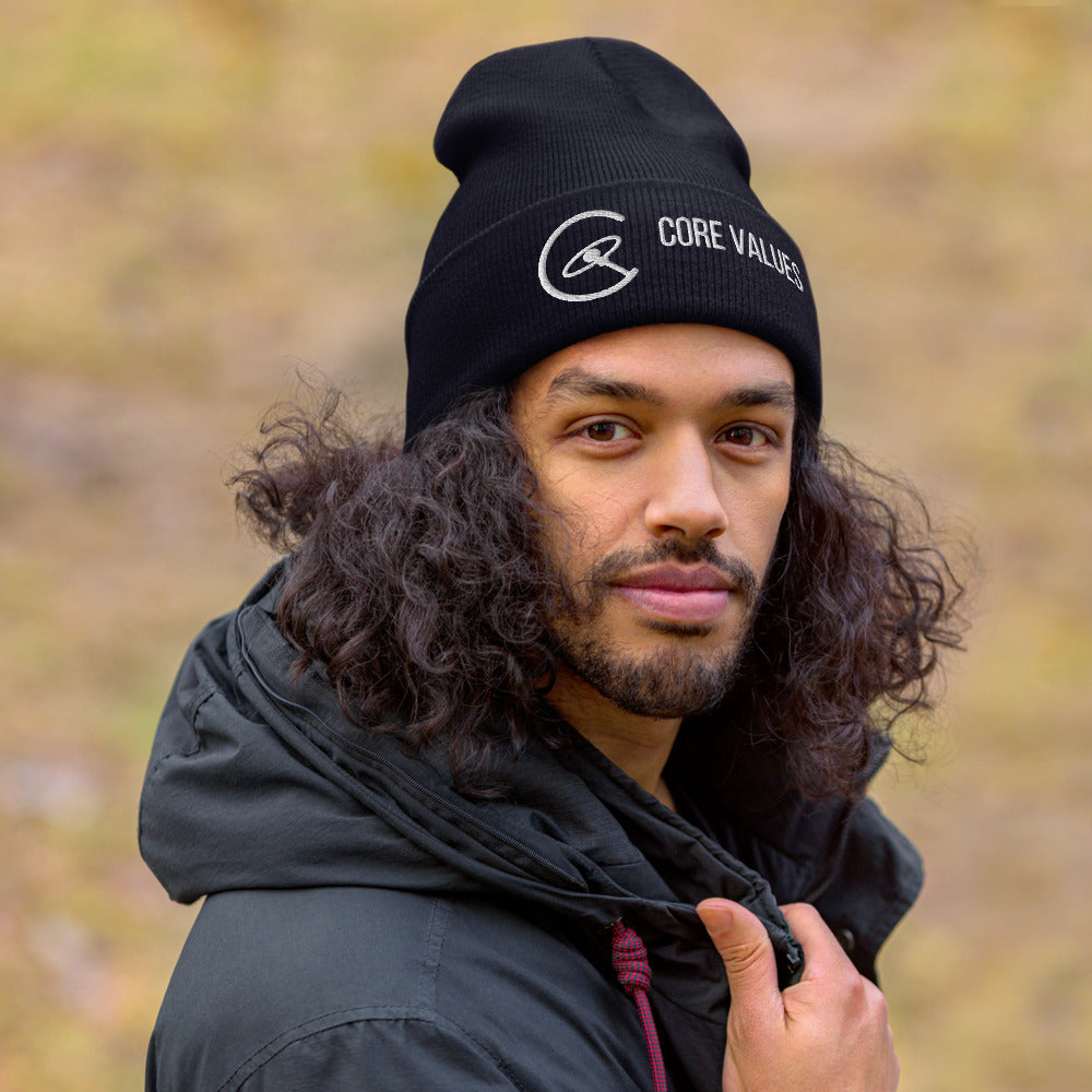 Man with long curly hair wearing the navy Core Values galaxy beanie outdoors on an autumn day