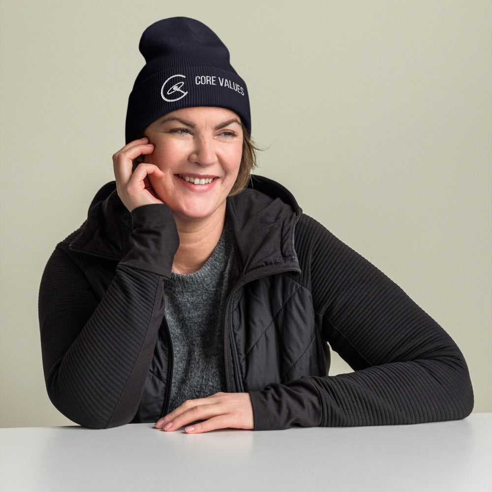 Smiling woman at a table wearing the navy Core Values galaxy beanie
