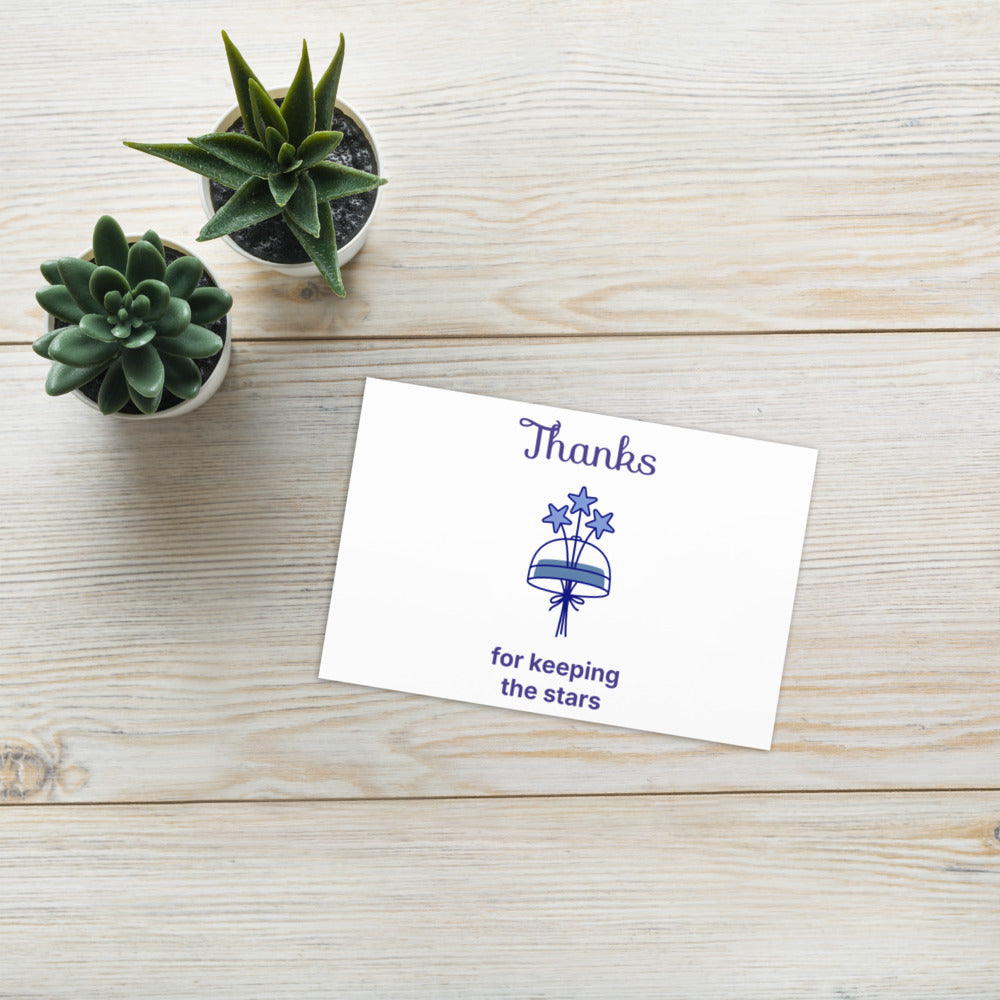 4x6 in dark sky thank you card with a star bouquet lying on a light wood table beside succulents