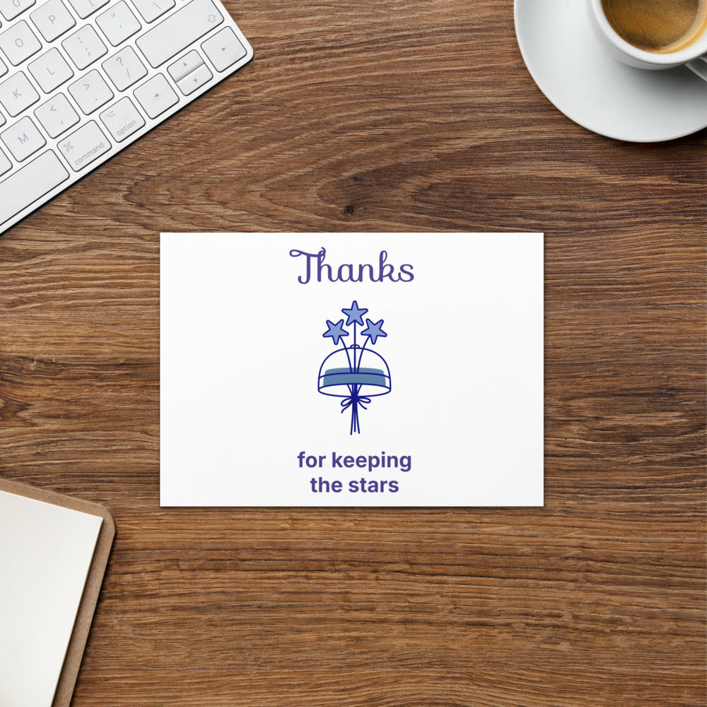 Dark sky thank you card, 5x7 in, with a three-star bouquet and Thanks for keeping the stars, on a wood desk by a keyboard and coffee