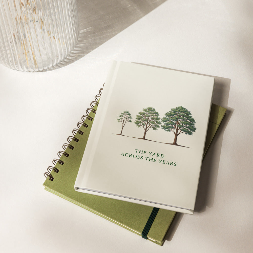 Nature journal on a table: three trees of growing size above THE YARD ACROSS THE YEARS on an ivory hardcover
