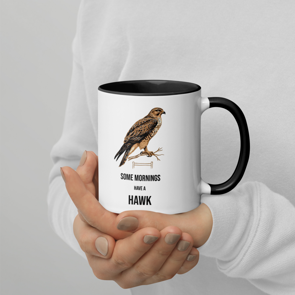 Hands holding the hawk mug with black inside, showing a brown hawk on a branch over SOME MORNINGS HAVE A HAWK