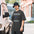Man in a bucket hat wearing a Faded Black funny astronomer shirt printed with DEW WATCH TECHNICIAN around a small telescope tube with a ringed-planet tag and a hanging water drop