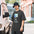 Man in a bucket hat wearing a Faded Black double star shirt printed with a thumb sliding a folded paper fan aside to show two stars and the gap between them above the words FIND THE GAP