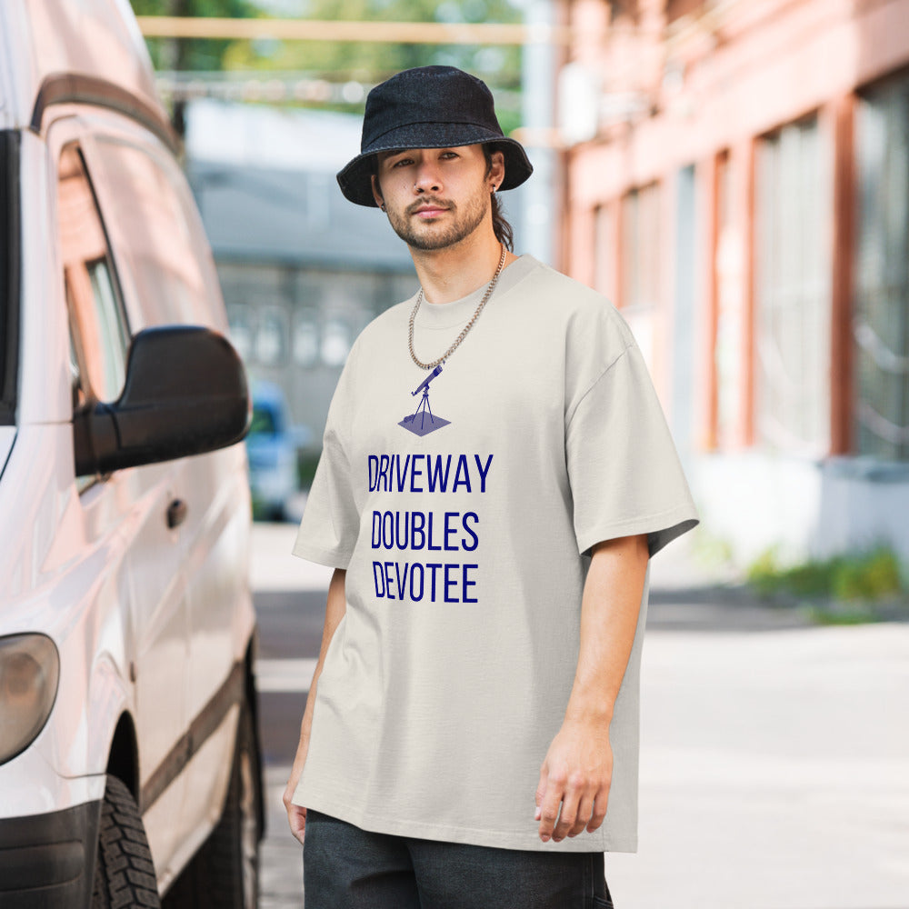 Man wearing the Faded Bone telescope shirt on a quiet street, small telescope on a tripod with a rolled star chart above the words DRIVEWAY DOUBLES DEVOTEE
