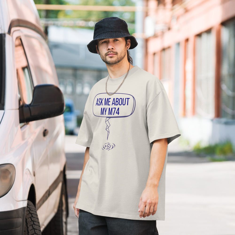 Man in a bucket hat wearing a Faded Bone messier shirt printed with a speech bubble reading ASK ME ABOUT MY M74 and a long zigzag tail ending at a small spiral galaxy