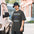 Man in a bucket hat wearing the Faded Coal Dew Watch Technician astronomy tee on a city street