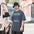 Man in a bucket hat wearing the Faded Indigo Dew Watch Technician astronomy tee on a city street