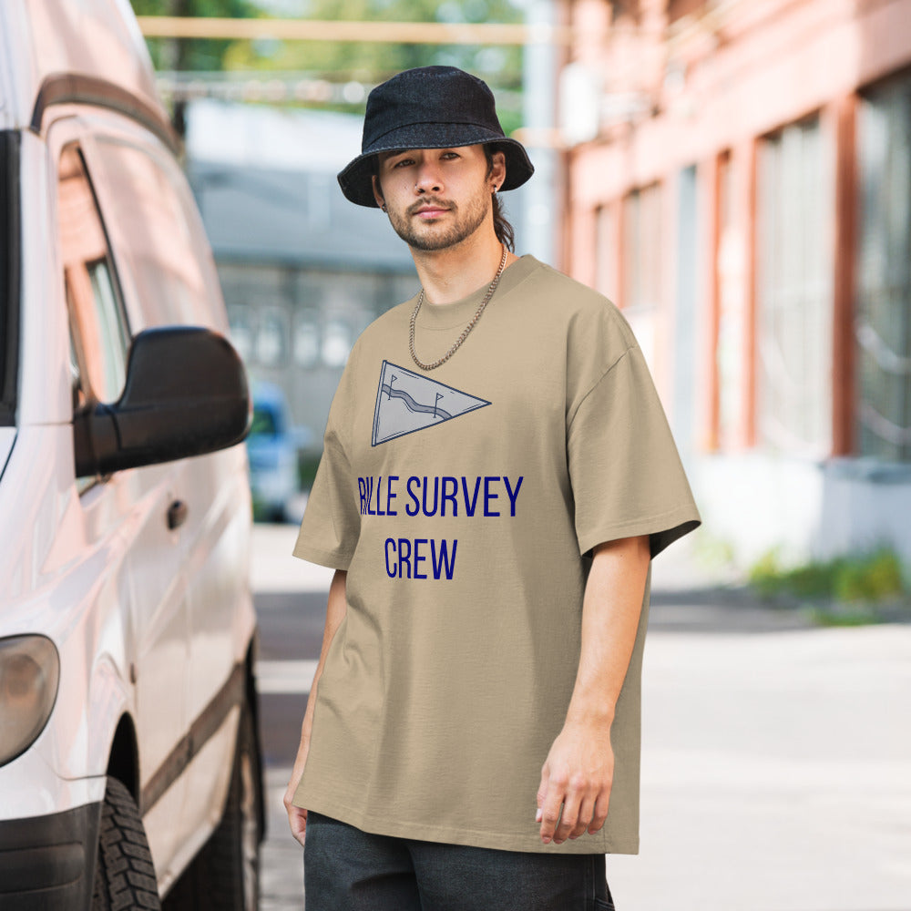 Man in a bucket hat wearing the Faded Khaki Rille Survey Crew tee on a city street beside a parked van