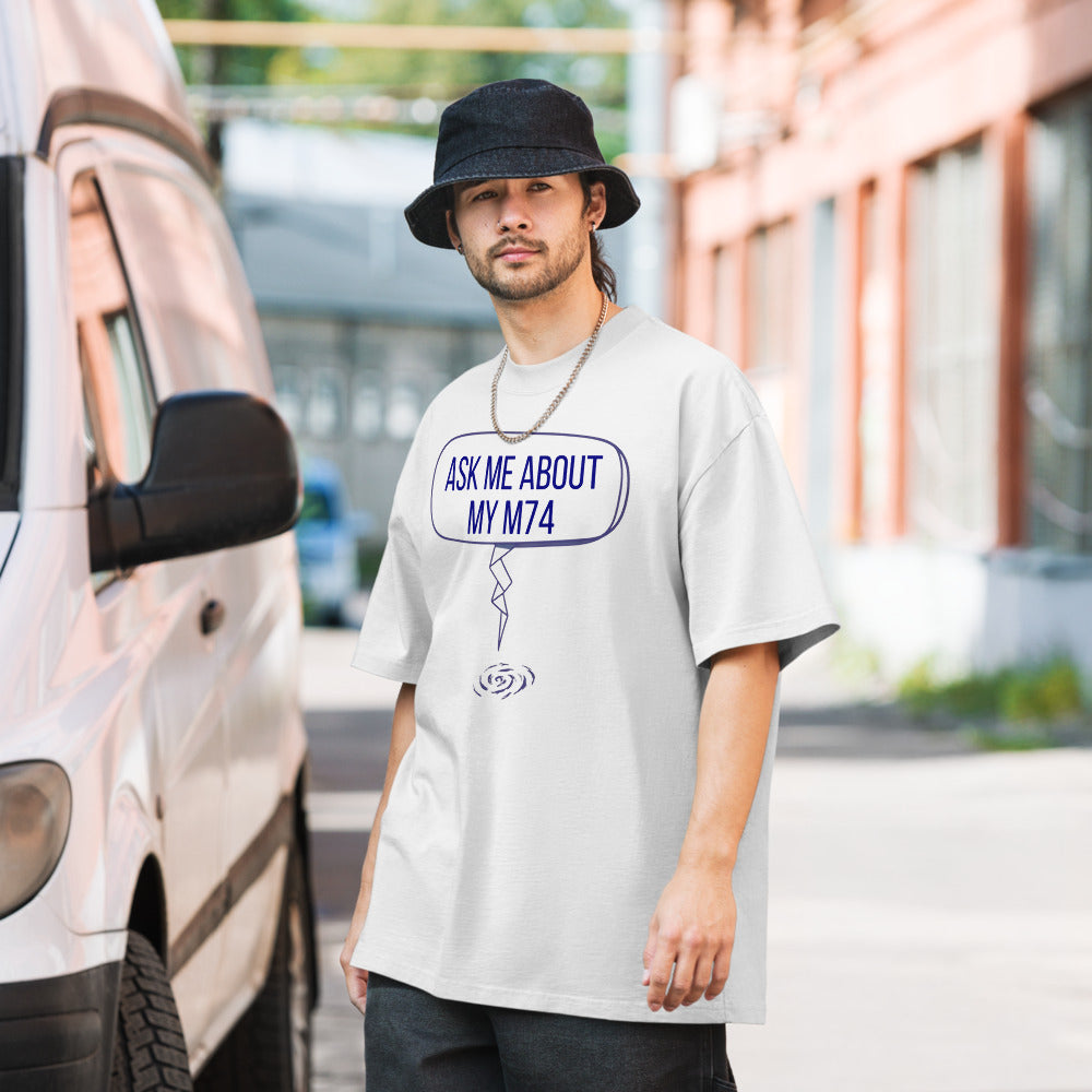 Man in a bucket hat wearing the Faded White Ask Me About My M74 galaxy tee on a city street