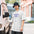 Man in a bucket hat wearing the Faded White Ask Me About My M74 galaxy tee on a city street