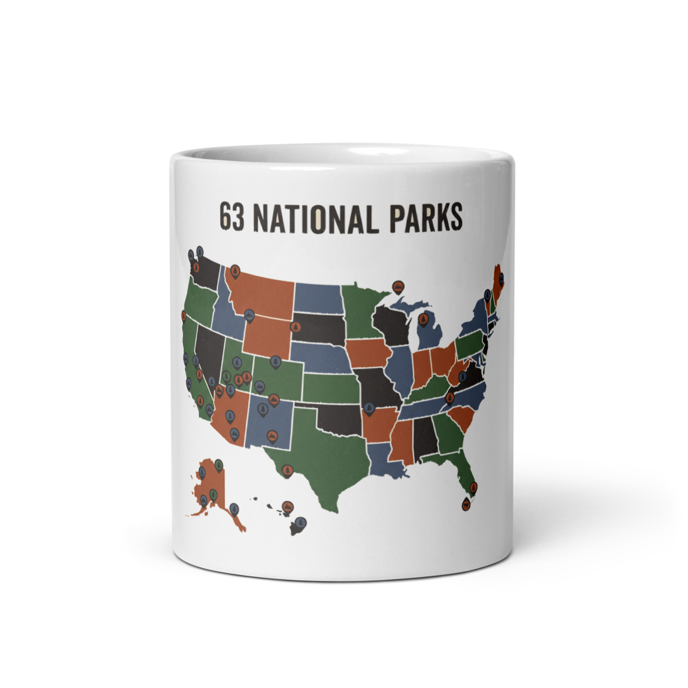 White glossy 11 oz ceramic mug printed with a vintage pin-marked United States map under the headline 63 National Parks