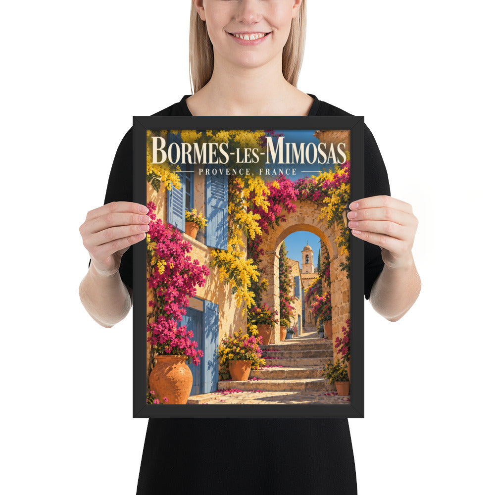 12″×16″ black-framed France travel poster of Bormes-les-Mimosas, shown with a person for scale
