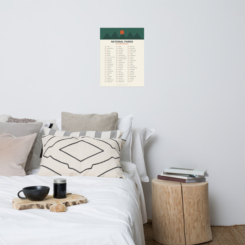 63-park national parks checklist poster above a bed with linen pillows and a wooden side table