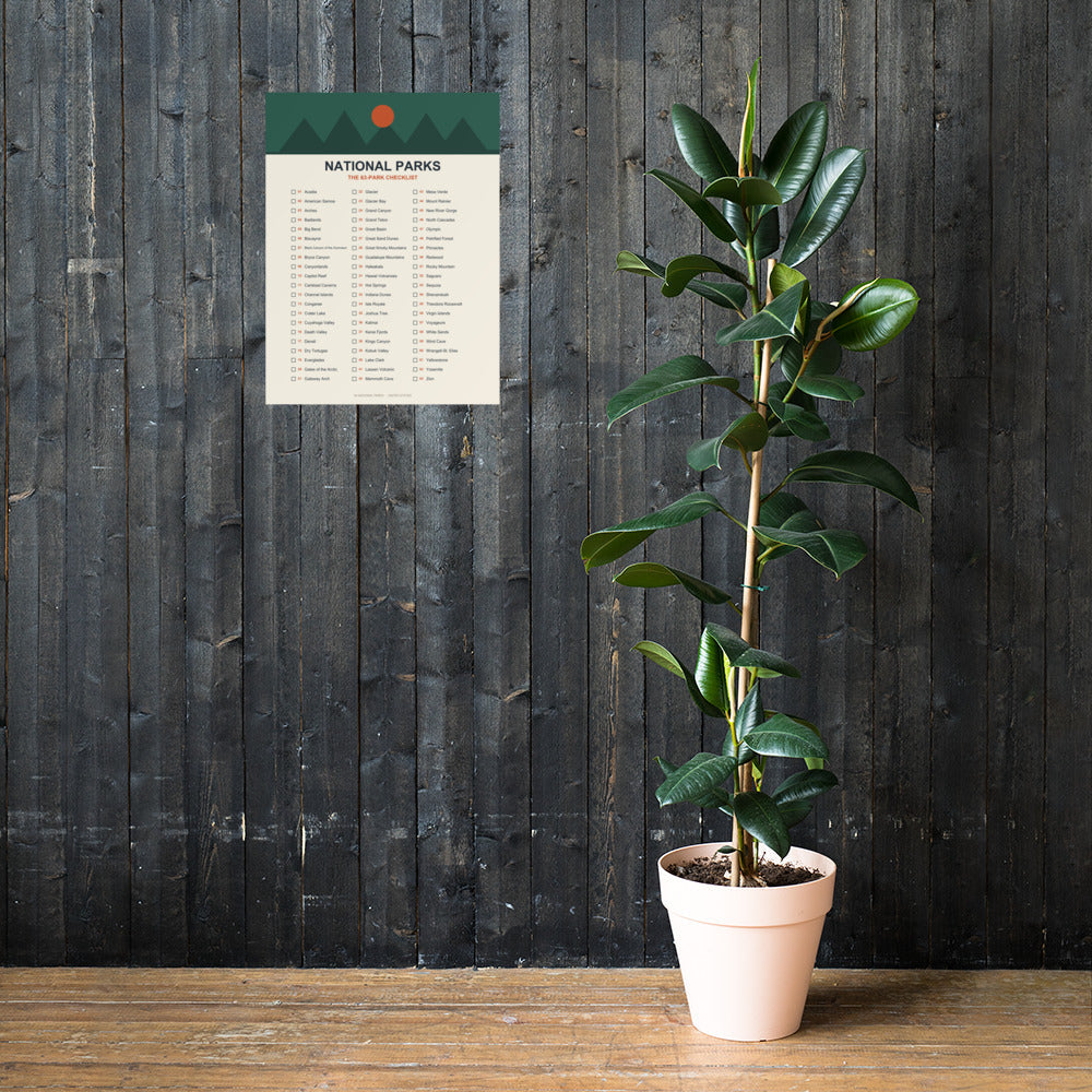 63-park national parks checklist poster on a dark stained wood plank wall beside a potted rubber plant