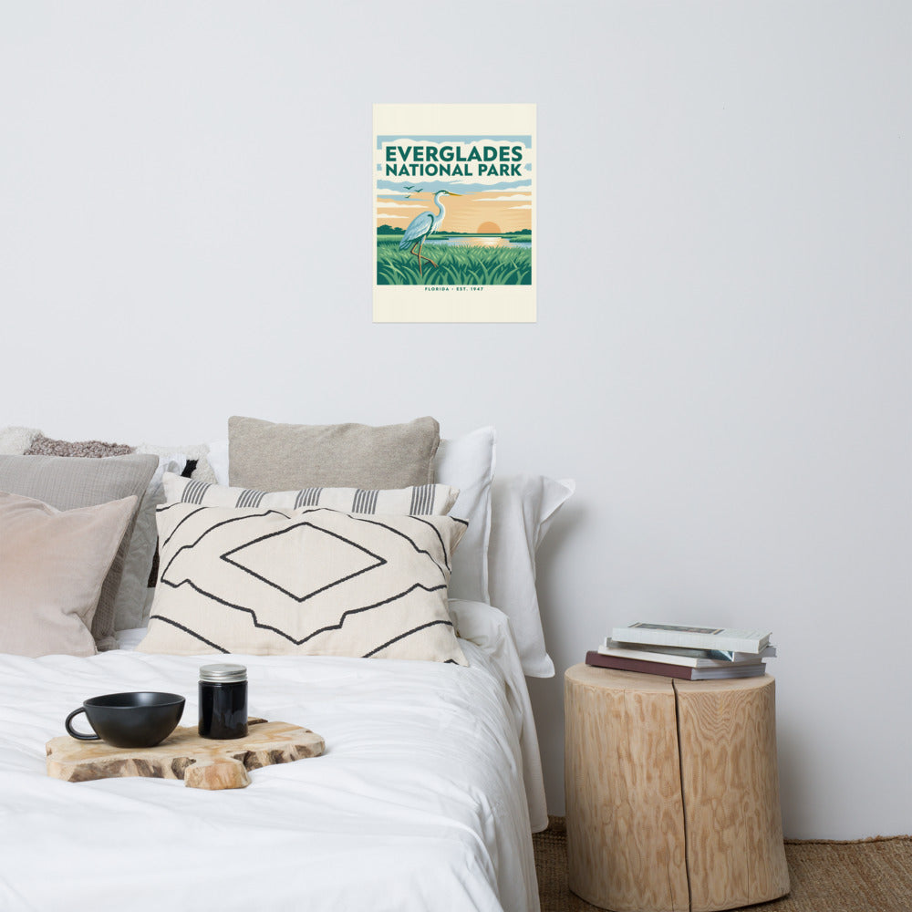 Everglades National Park vintage travel poster with a great blue heron over sawgrass at sunset, hanging above a bed in a styled bedroom