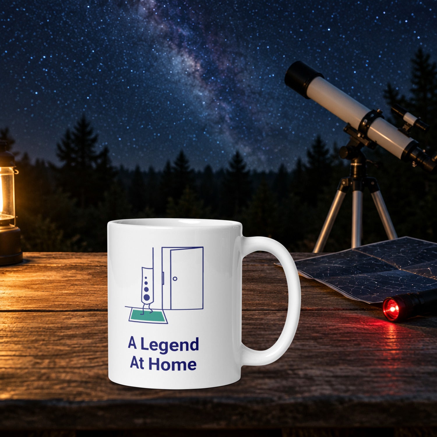 A Legend at Home star atlas mug on a wooden observing table at night beside a folded star chart, red flashlight and white telescope under the Milky Way