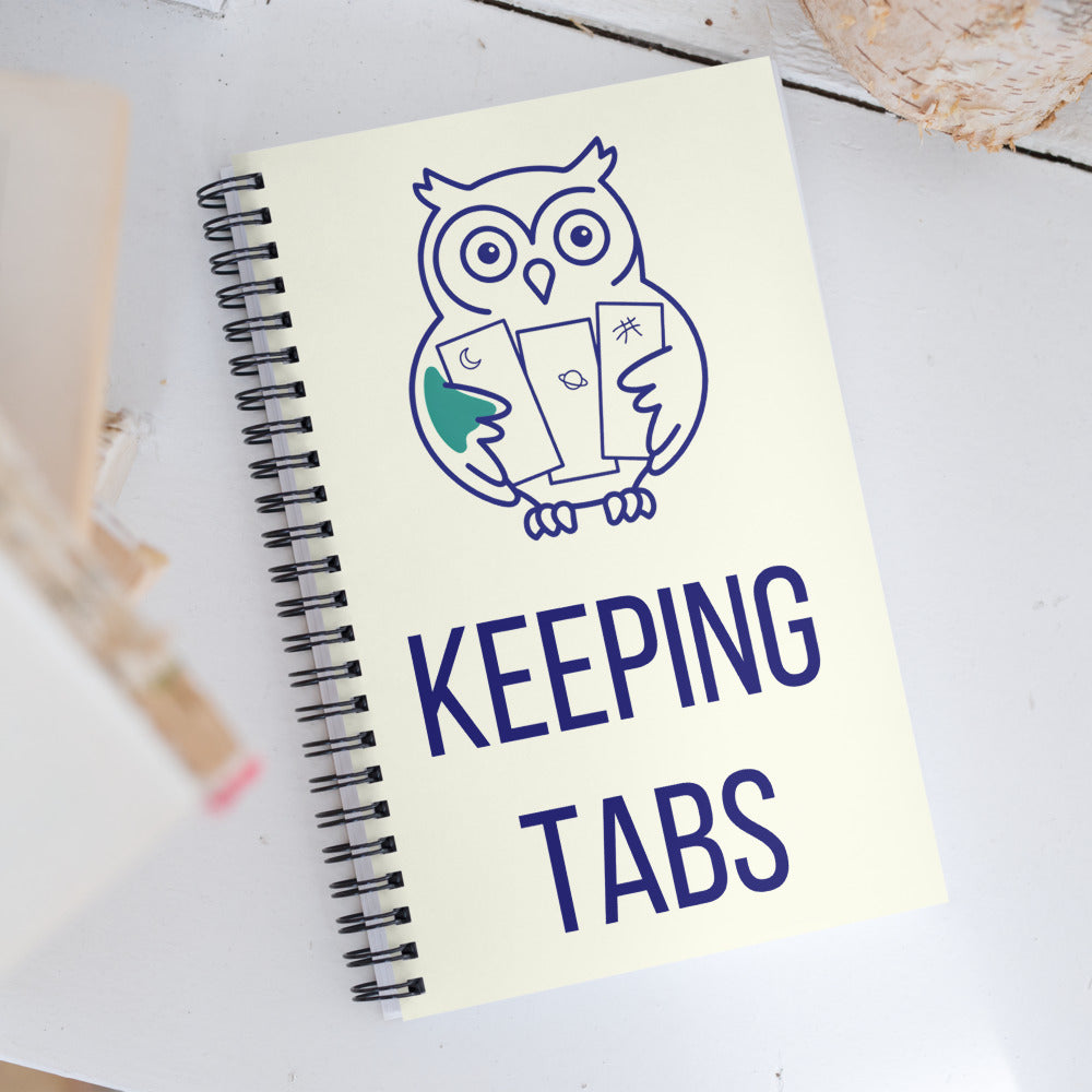 Keeping Tabs owl astronomy notebook resting on a white wooden table next to a stack of books