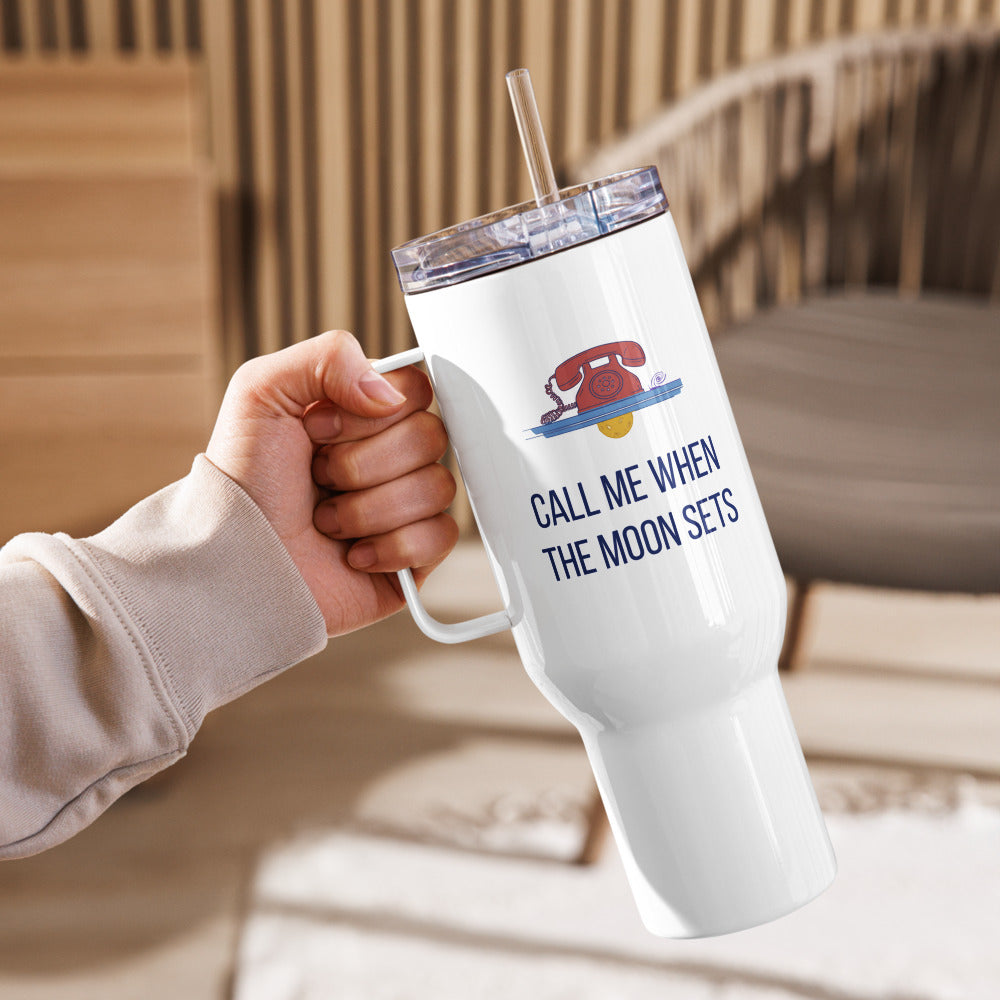Hand raising the Call Me When the Moon Sets 40 oz straw travel mug in a cozy living room