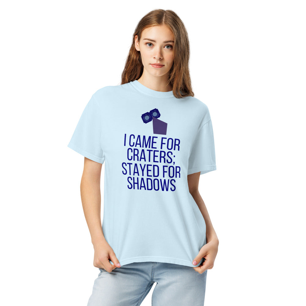 Woman wearing the Chambray lunar observer shirt, front view, printed with binoculars drawn as a ticket casting a long shadow above I CAME FOR CRATERS; STAYED FOR SHADOWS
