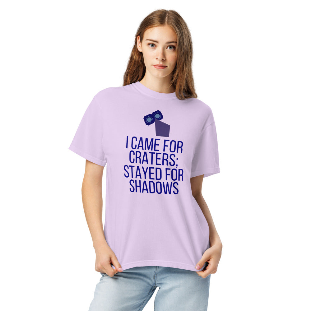 Woman wearing the Orchid lunar observer shirt, front view, printed with binoculars drawn as a ticket casting a long shadow above I CAME FOR CRATERS; STAYED FOR SHADOWS