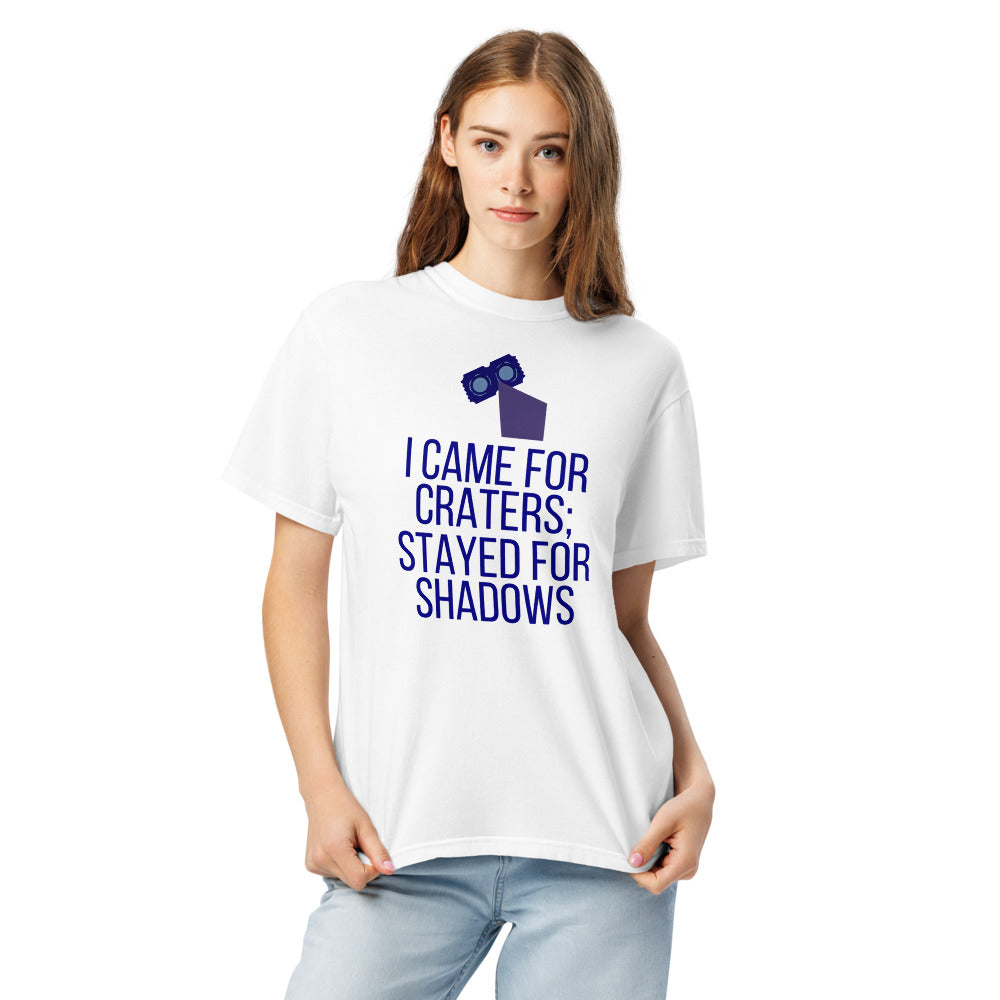 Woman wearing the White lunar observer shirt, front view, printed with binoculars drawn as a ticket casting a long shadow above I CAME FOR CRATERS; STAYED FOR SHADOWS