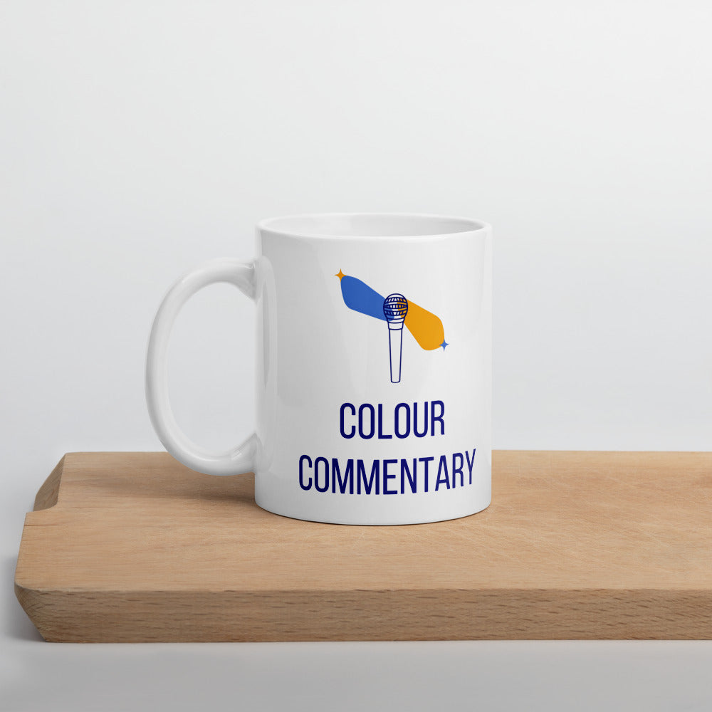 Colour Commentary double star mug standing on a wooden board, microphone with blue and gold star streaks above the navy lettering