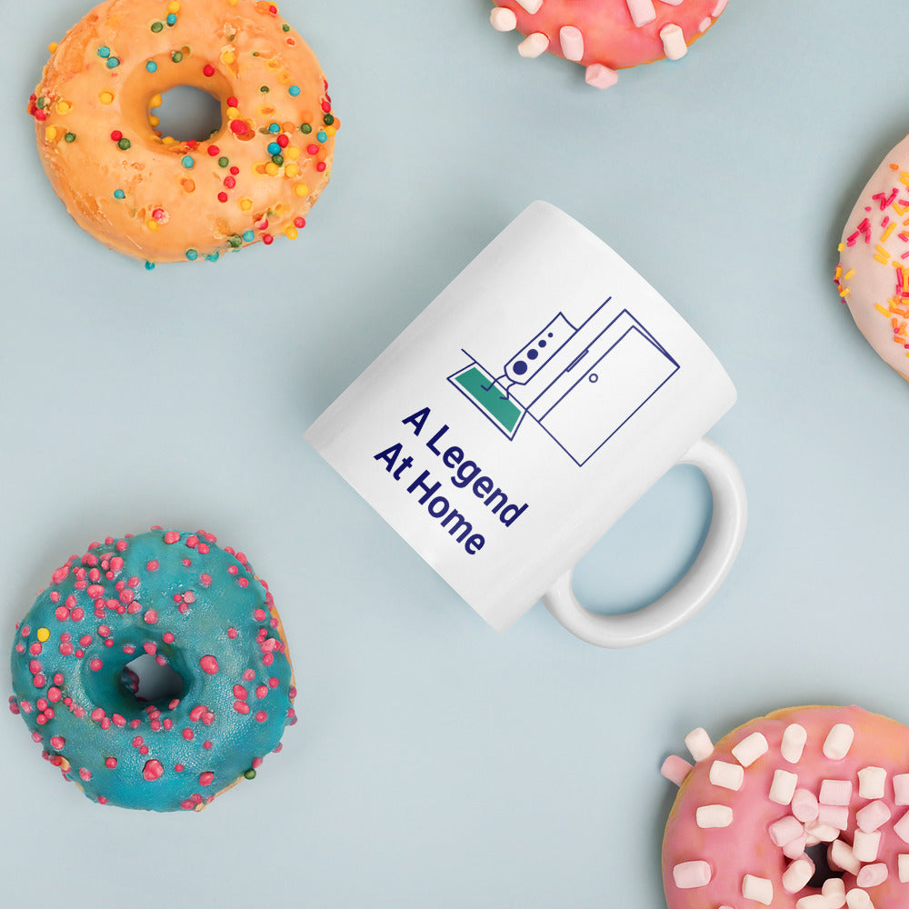 A Legend at Home astronomy mug lying among sprinkled donuts on a pale blue table