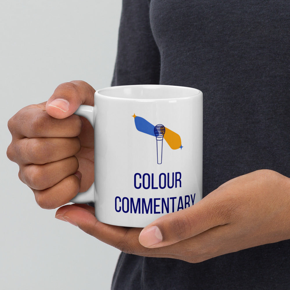 Hand holding the double star mug by its handle, the Colour Commentary microphone and star streaks facing out