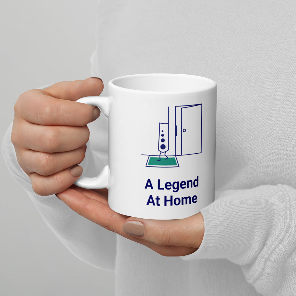 Hand holding the 11 oz A Legend at Home mug by the handle, showing the design printed on the handle-left side